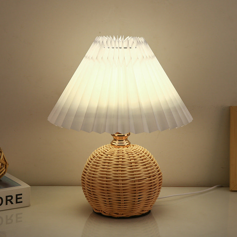 Contemporary Nordic Rattan Pleated LED Table Lamp for Bedroom 

Enhance your bedroom decor with this stylish contemporary Nordic rattan fabric table lamp. Featuring a unique pleated conic design, this LED lamp offers a warm, inviting glow while showcasing