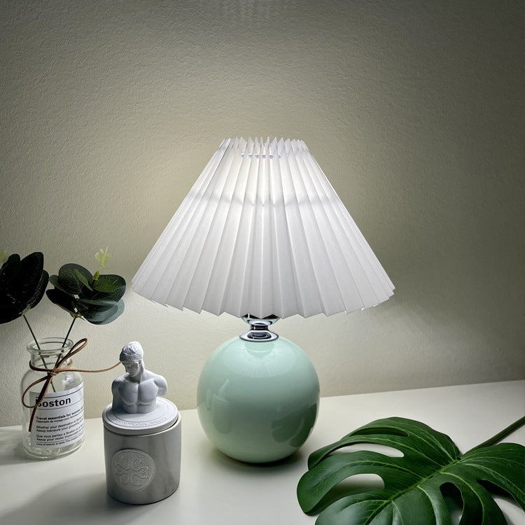 Modern Minimalist Round Fabric Pleated Ceramic 1-Light Table Lamp for Bedroom | Stylish Bedside Lighting | Contemporary Home Decor | Elegant Bedroom Accent | Soft Ambient Illumination | Decorative Lighting Fixture | Chic Fabric Shade | Ceramic Base Design